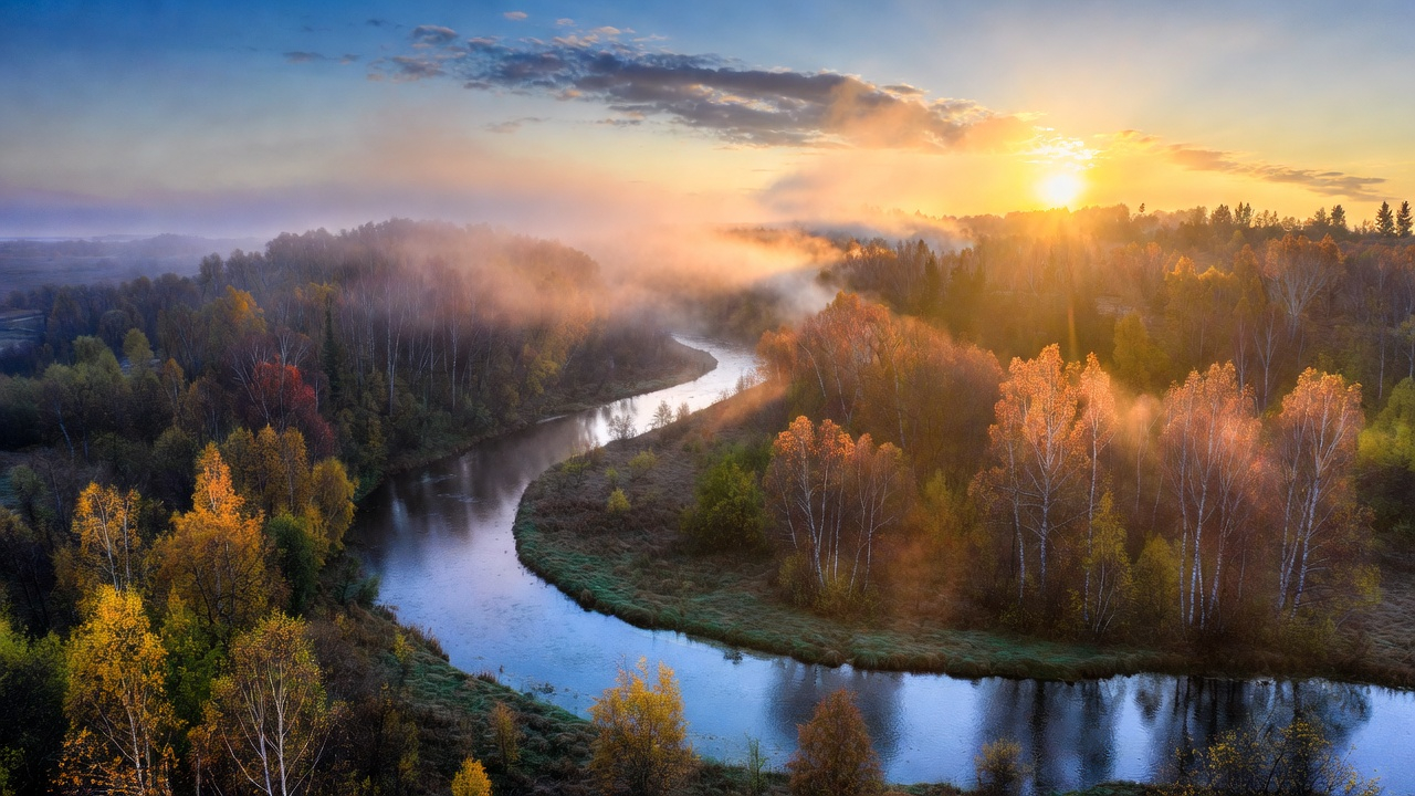 A peaceful autumn landscape with a winding river at sunset, symbolizing Divine Timing and the flow of Source Energy.